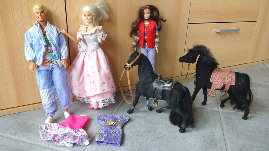 3 Barbiepuppen, Kleider, 2 Pferde und 1 größerer Teddybär.