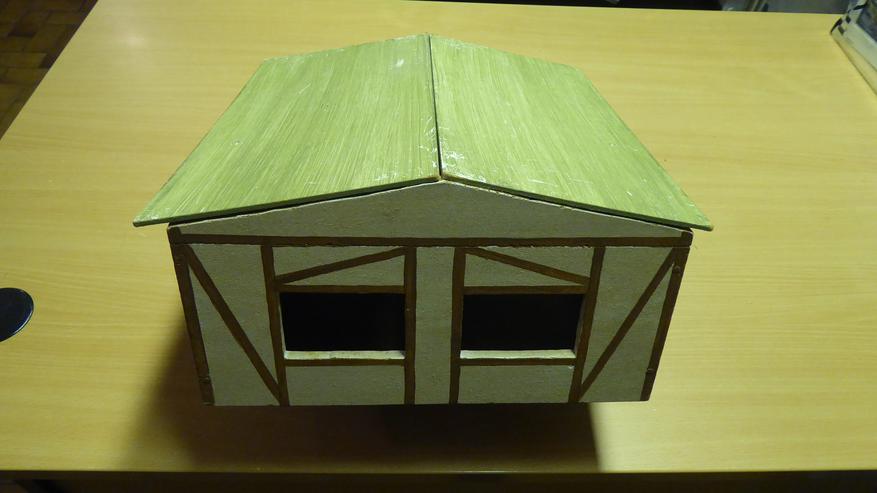 Holzstall mit aufgemaltem Fachwerk und abnehmbaren Dach